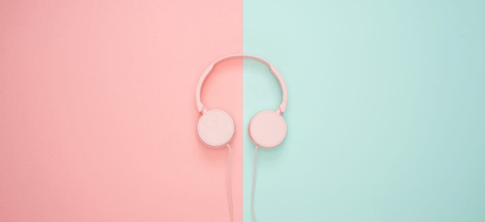 photo of pink headphones laying on a bicolored surface of pink and aqua.