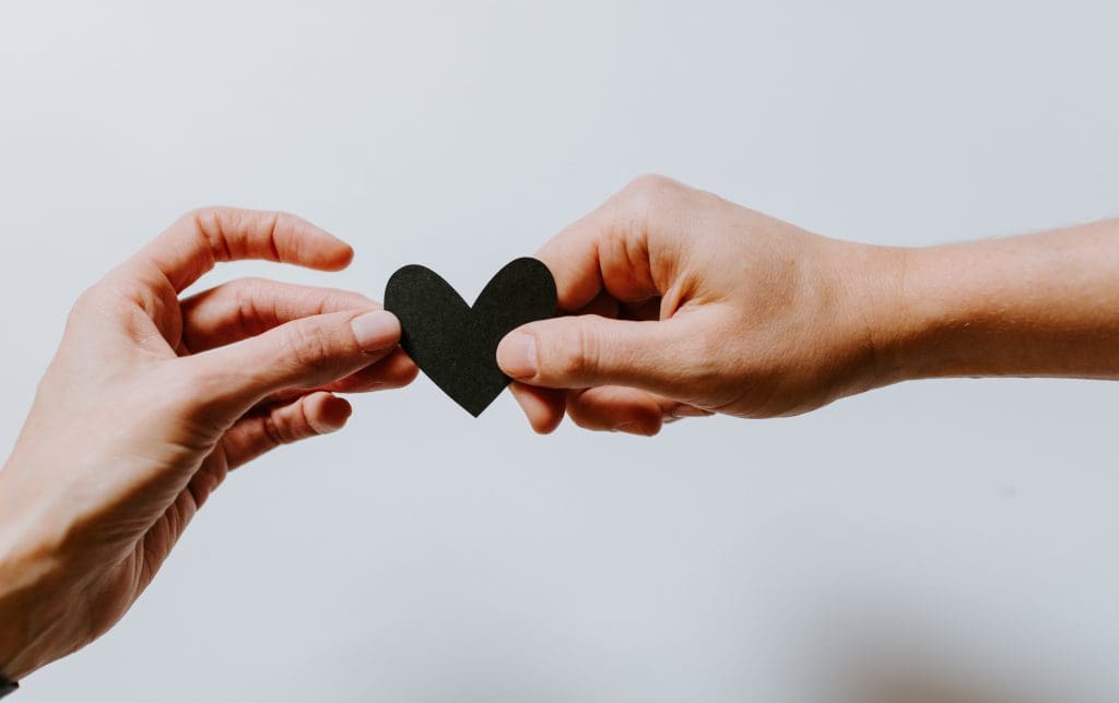 One hand passing a heart to another