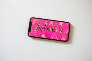 Phone on a table displaying the word anxiety on a pink and green background