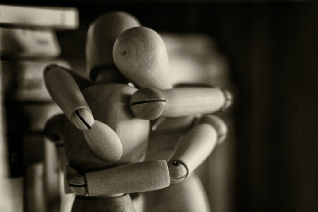 This is a photo of two wooden dolls embracing one another in a hug.