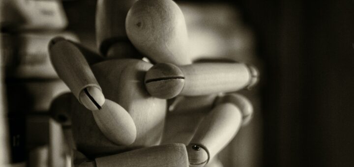 This is a photo of two wooden dolls embracing one another in a hug.
