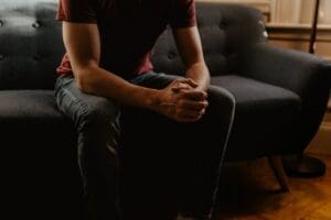 this is a picture of a person sitting on a couch with his/her hands crossed. You cannot see the person's face.