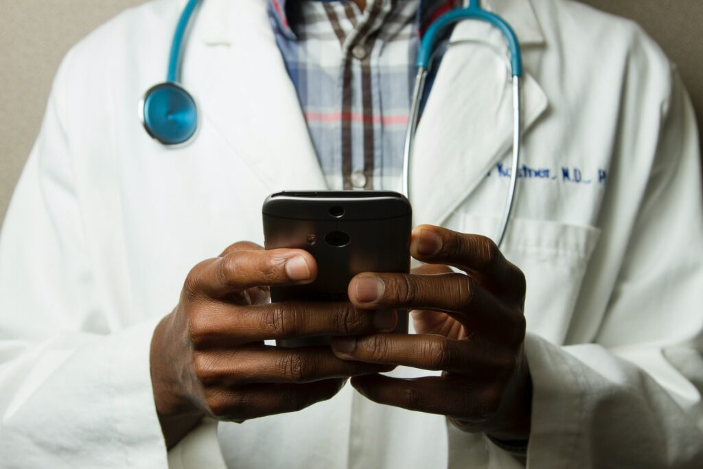 picture of hands holding a phone; person is wearing a lab coat and is a doctor
