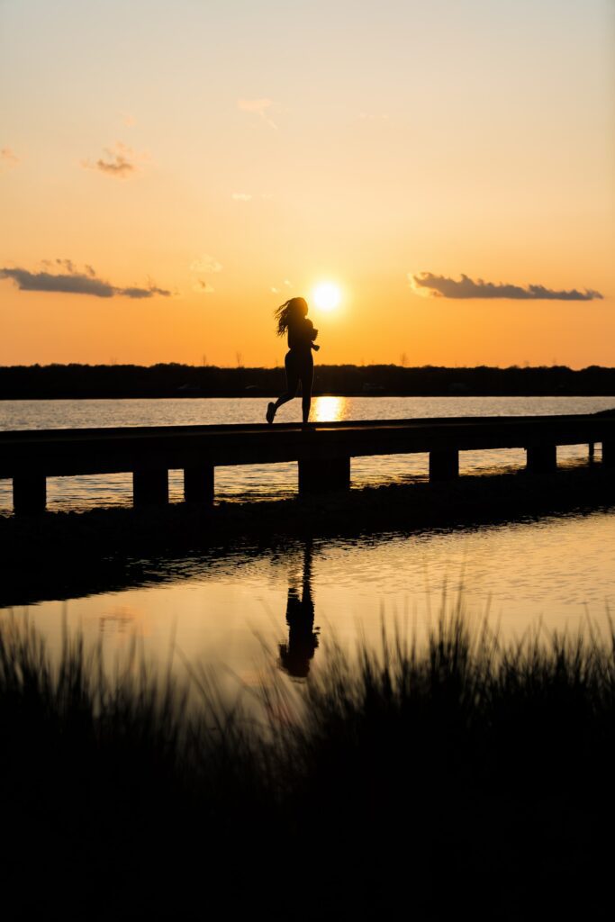 This is a picture of a woman running in the sunset/sunrise and all you see is her silhouette. 