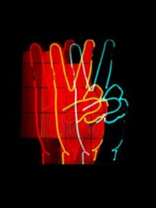 this is a picture of neon sign that is three hands making the peace sign.