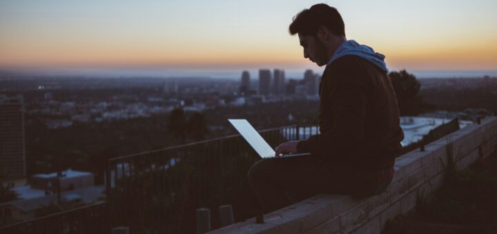 man at computer/ city sunset